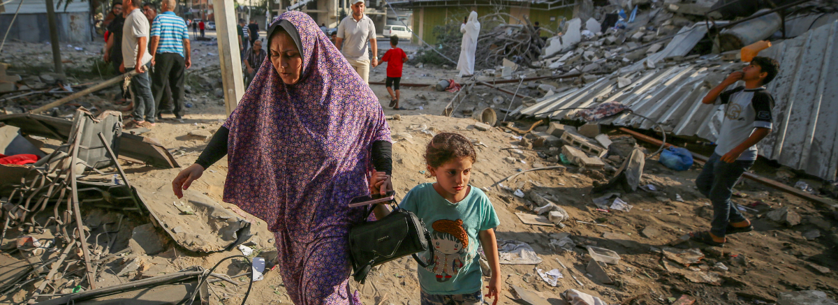 A woman and a child walk through a demolished area