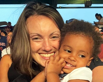 Jessica Lynn smiles at camera hugging child