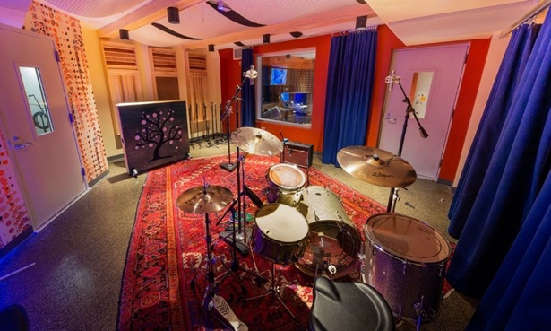 Studio B at The Record Co. - a warmly lit recording studio with a red carpet and a drum set in the center of the room.