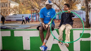 Playworks coach and student talk on playground
